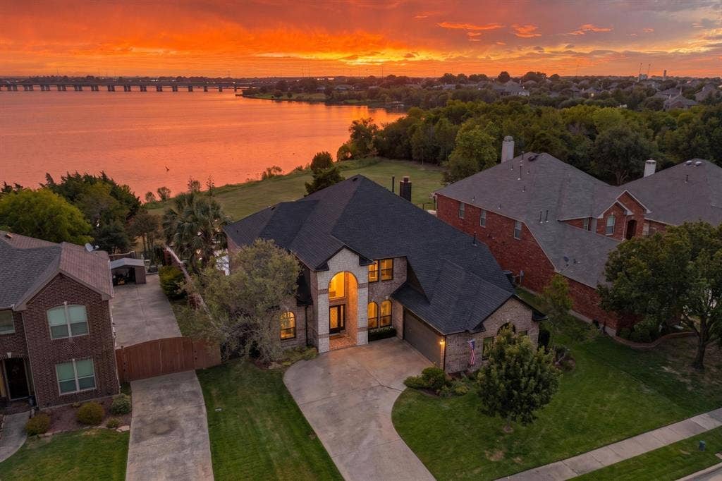 4016 Stone Haven Drive, Garland, TX 75043 Stately residence featuring a brick and stone exterior, arched entryway, attached garage, and mature landscaping