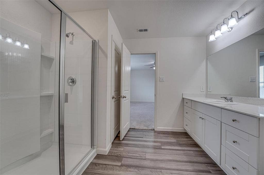 767 Camden Drive, Lavon, TX 75166 Glass-enclosed shower with subway tile surround, double vanity with quartz-finish countertop, and wood-finish flooring