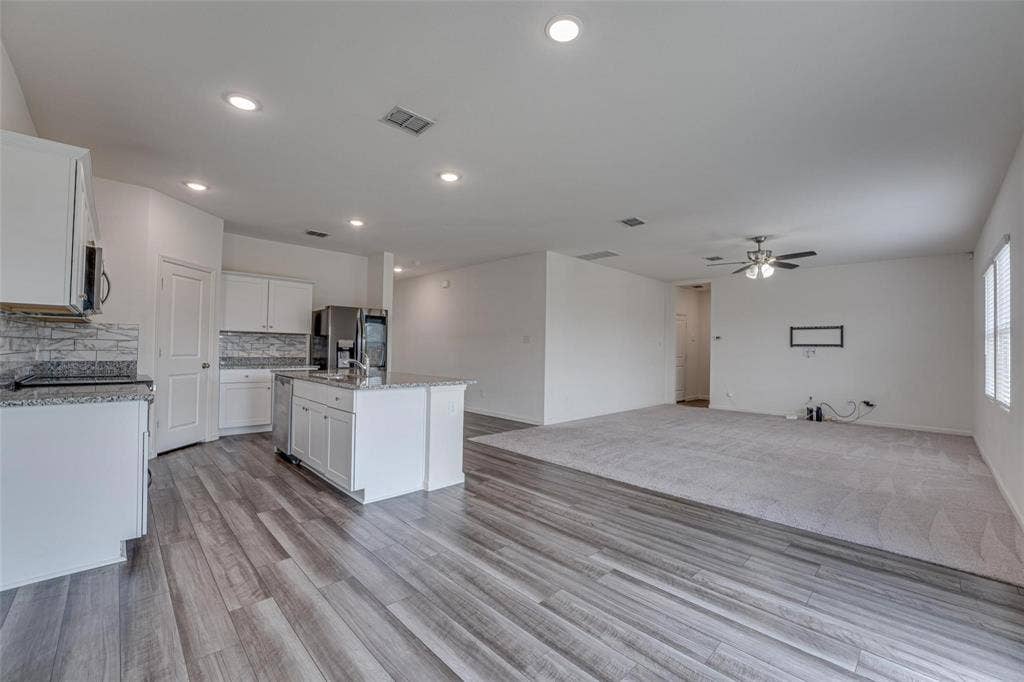 767 Camden Drive, Lavon, TX 75166 Open concept kitchen featuring white cabinetry, a kitchen island, stainless steel appliances, and wood-finish flooring