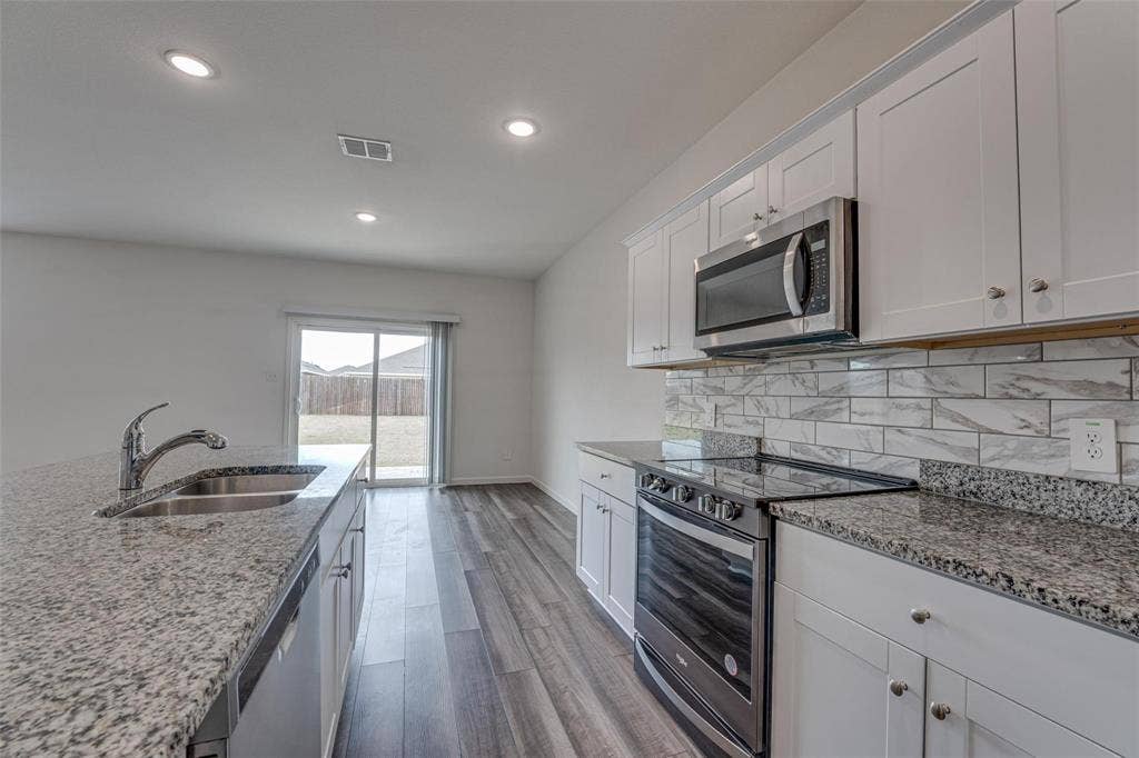 767 Camden Drive, Lavon, TX 75166 Kitchen featuring granite countertops, a stainless steel oven with a glass cooktop, a stainless steel microwave, white cabinetry, and wood-finish flooring