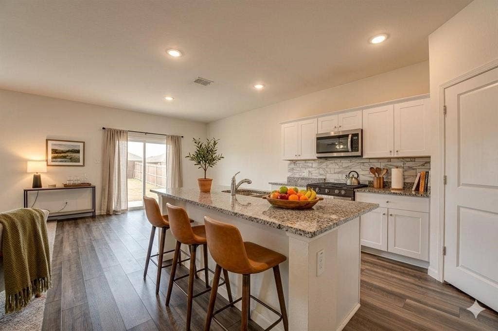 767 Camden Drive, Lavon, TX 75166 Kitchen island with granite countertop, stainless steel appliances, white cabinetry, wood-finish flooring, and recessed lighting