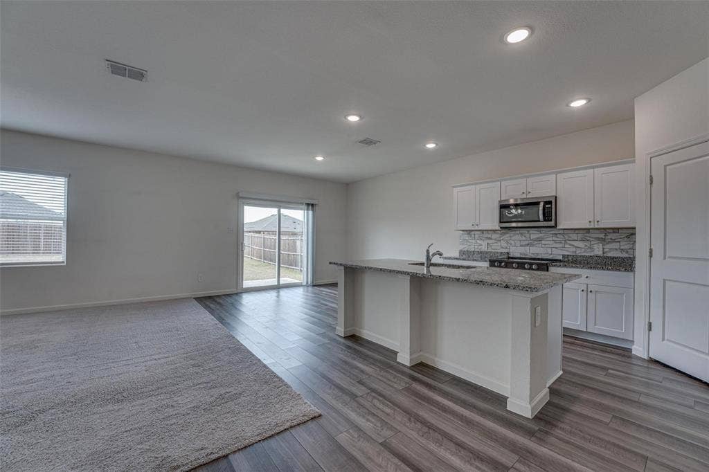 767 Camden Drive, Lavon, TX 75166 Recessed lighting, wood-finish flooring, white cabinetry, integrated microwave, and a sliding glass door
