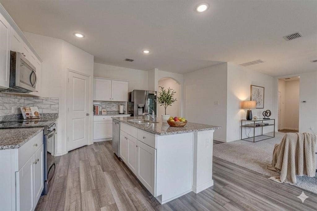 767 Camden Drive, Lavon, TX 75166 Modern kitchen featuring a central island, white cabinetry, granite countertops, and stainless steel appliances