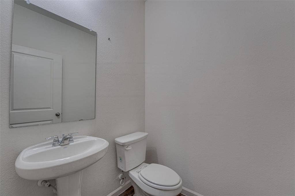 767 Camden Drive, Lavon, TX 75166 Pedestal sink with chrome fixtures, wall-mounted mirror, and white toilet