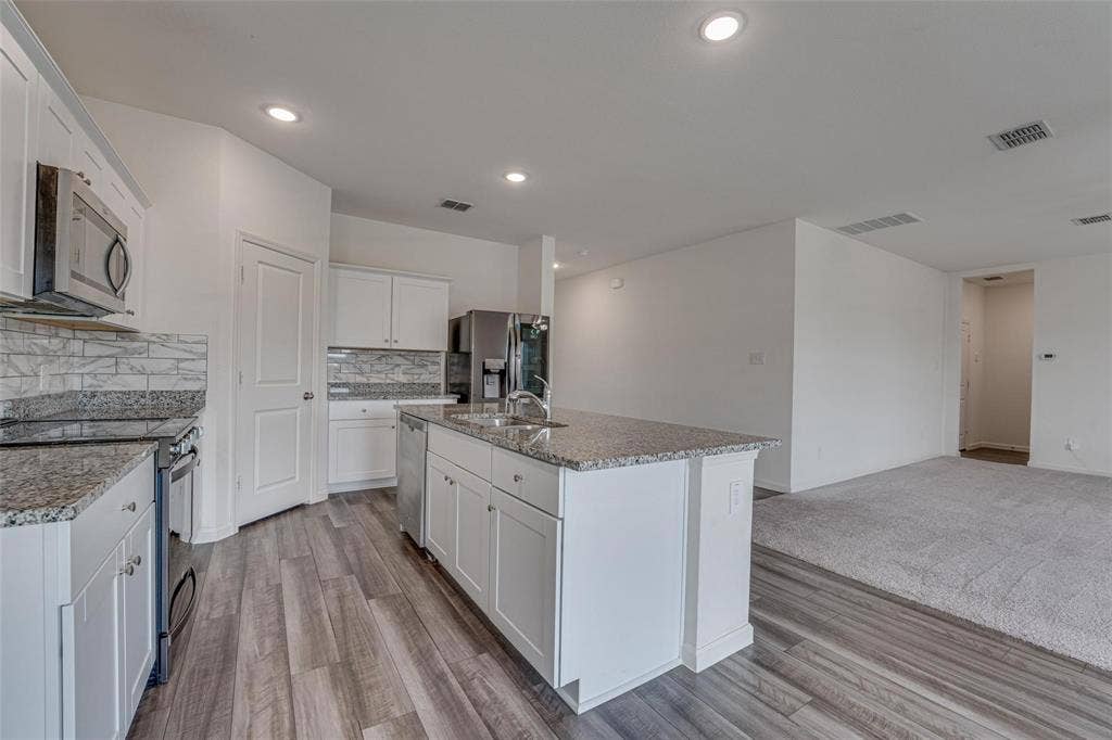 767 Camden Drive, Lavon, TX 75166 Kitchen featuring white shaker cabinetry, stainless steel appliances, granite countertops, and wood-finish flooring