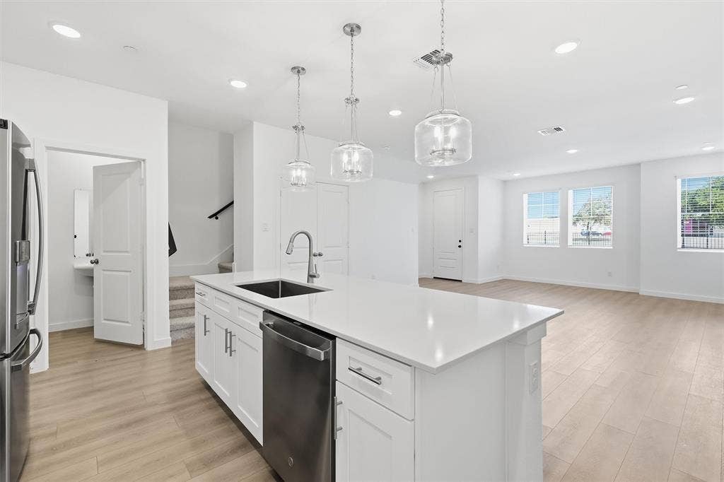 7621 Dakota, Watauga, TX 76148 Kitchen island with white cabinetry, stainless steel appliances, and a solid surface countertop