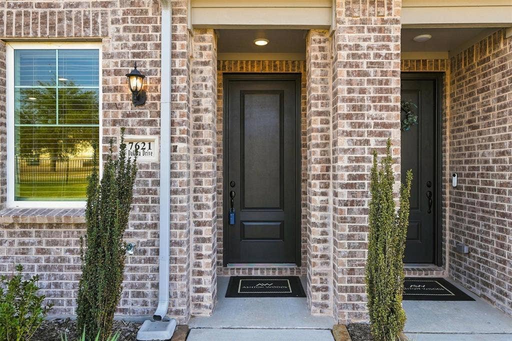 7621 Dakota, Watauga, TX 76148 Brick exterior with a prominent entrance, white frame window, and outdoor wall sconce