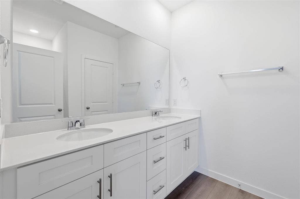 7621 Dakota, Watauga, TX 76148 Double vanity with white cabinetry, integrated sinks, chrome fixtures, and a large wall-mounted mirror