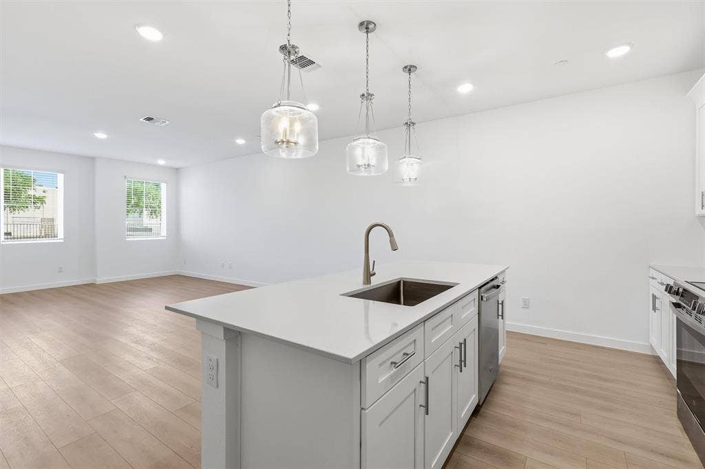 7621 Dakota, Watauga, TX 76148 Kitchen island with an undermount sink, gooseneck faucet, and white shaker cabinetry