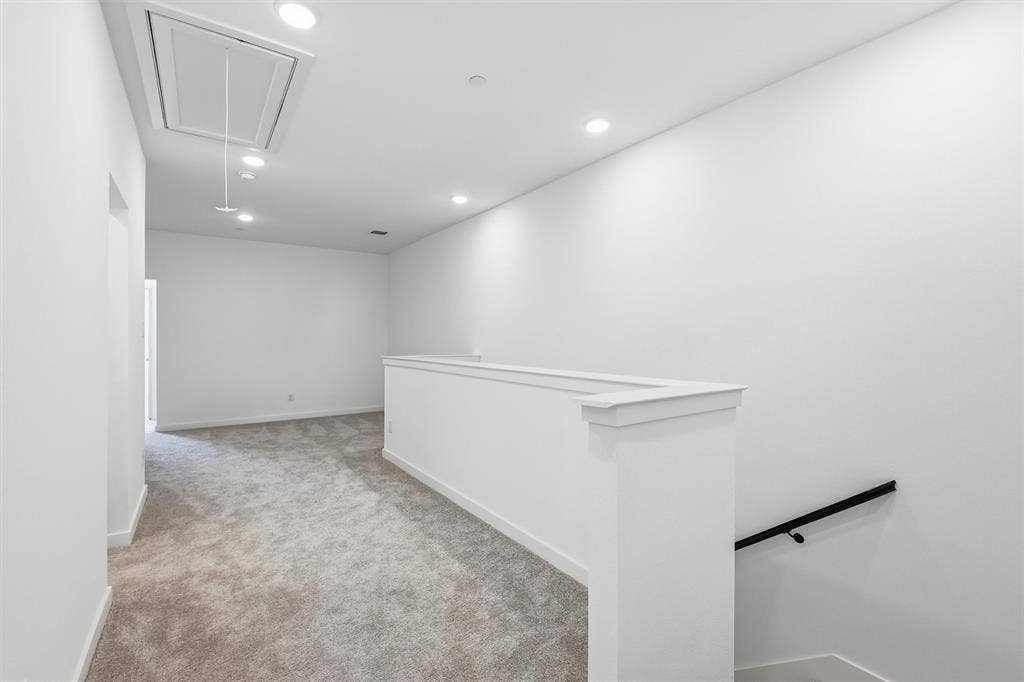 7621 Dakota, Watauga, TX 76148 Carpeted hallway with a white half-wall railing, recessed ceiling lighting, and a black handrail