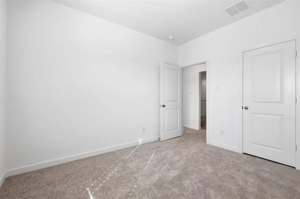 7621 Dakota, Watauga, TX 76148 Neutral tone wall paint, light-colored carpet flooring, white trim, and white paneled doors with hardware