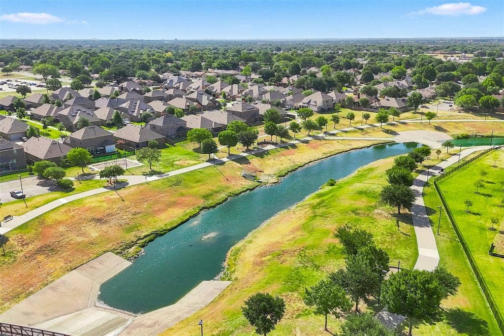 7621 Dakota, Watauga, TX 76148 Residential community with mature tree coverage, featuring a water channel, pedestrian pathways, and open green spaces