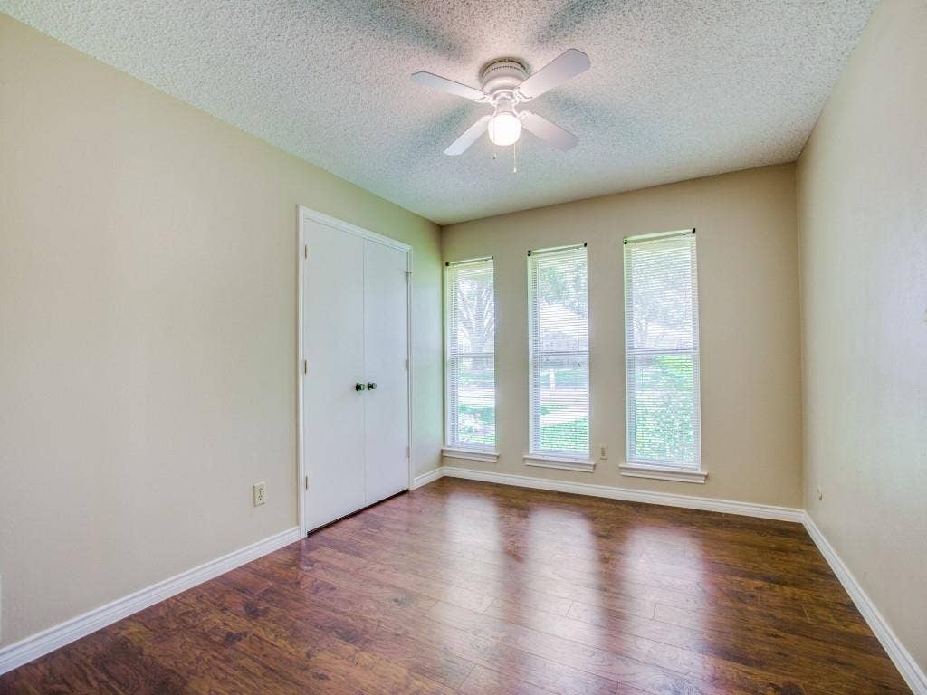 1103 Sundial Drive, Richardson, TX 75081 Warm wood-finish flooring, three vertical windows, and a ceiling fan with integrated lighting