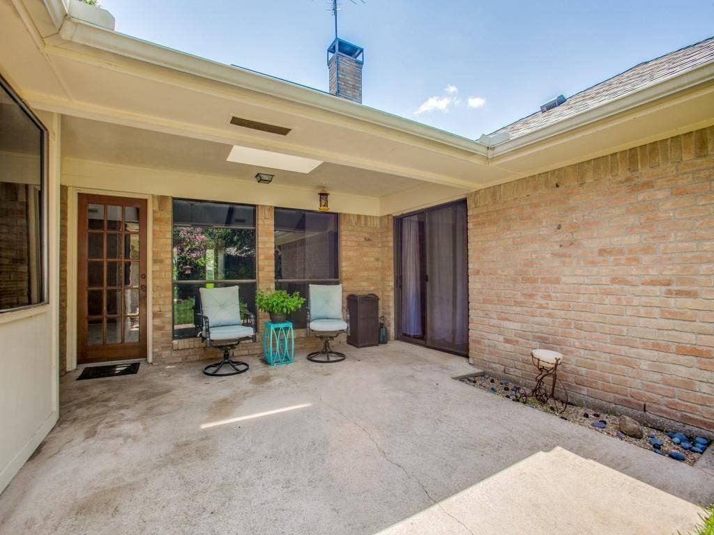 1103 Sundial Drive, Richardson, TX 75081 Covered concrete patio with brick exterior, a wood-frame glass panel door, and a sliding glass door