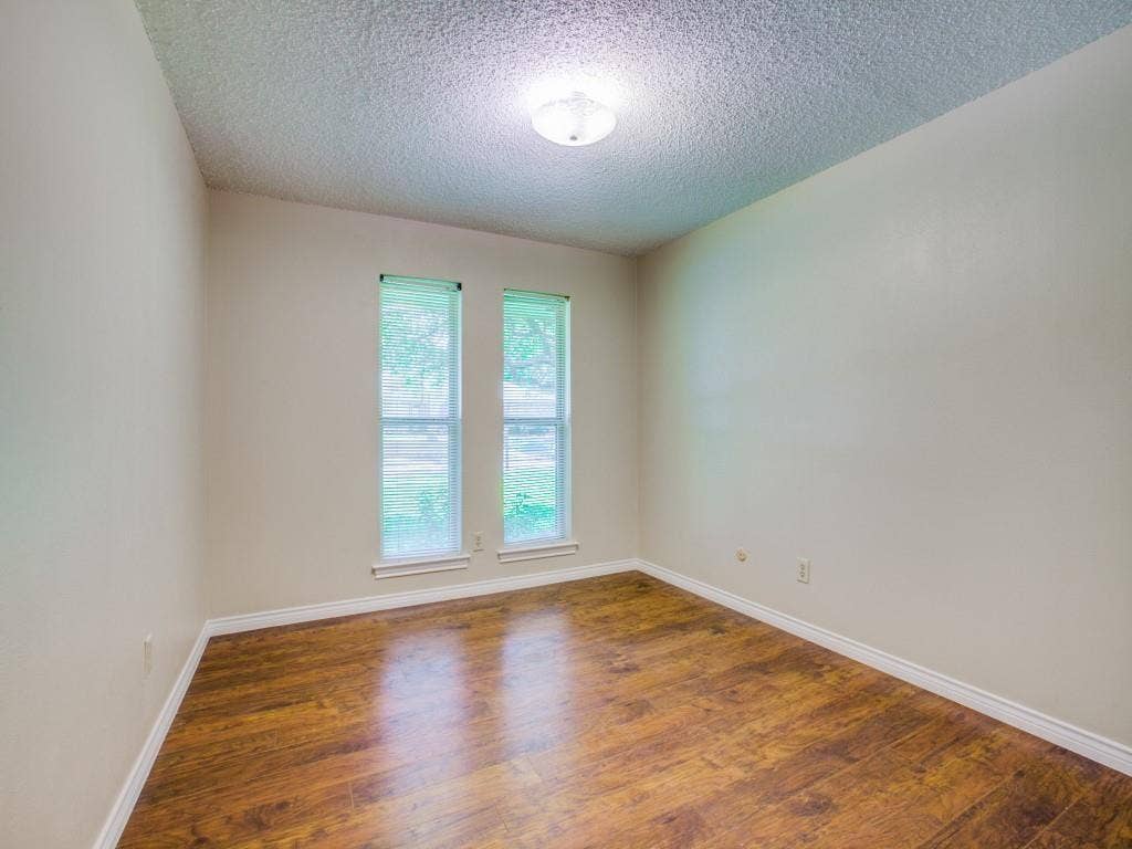 1103 Sundial Drive, Richardson, TX 75081 Neutral wall paint with wood-finish flooring, two large windows, and a flush mount ceiling light fixture