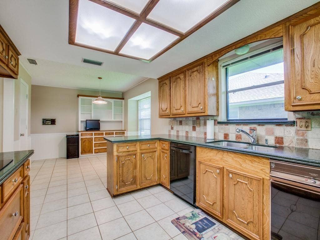 1103 Sundial Drive, Richardson, TX 75081 Kitchen featuring wood cabinetry, dark countertops, tiled flooring, integrated appliances, and a rectangular window