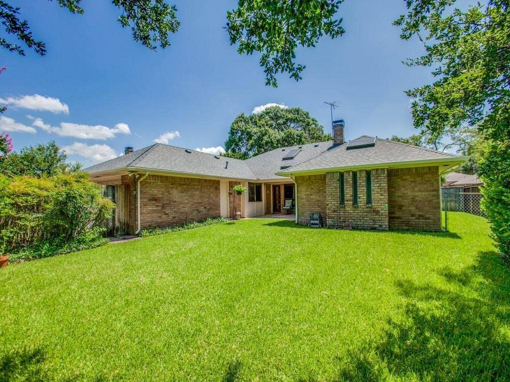 1103 Sundial Drive, Richardson, TX 75081 Expansive lawn area with mature landscaping, brick exterior, and a shingled roofline