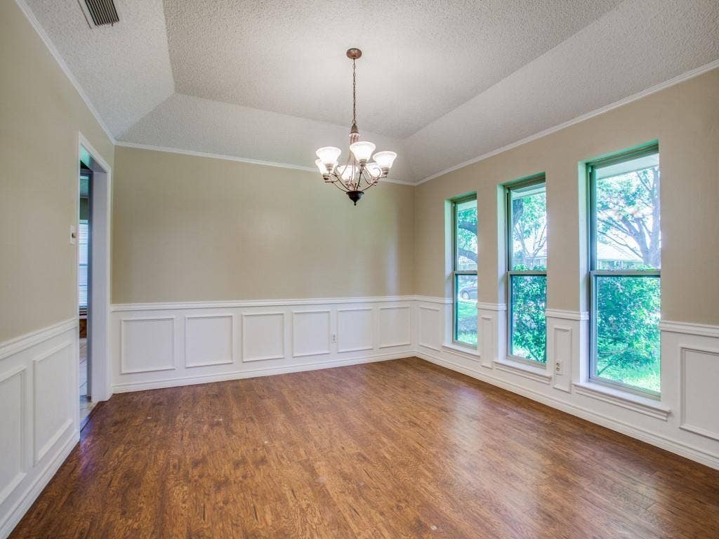 1103 Sundial Drive, Richardson, TX 75081 Tray ceiling with crown molding, wood-finish flooring, white wainscoting, and a multi-light chandelier