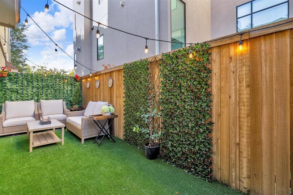 4242 Travis Street, #102, Dallas, TX 75205 Fenced outdoor area featuring artificial turf, string lighting, and vertical foliage panels