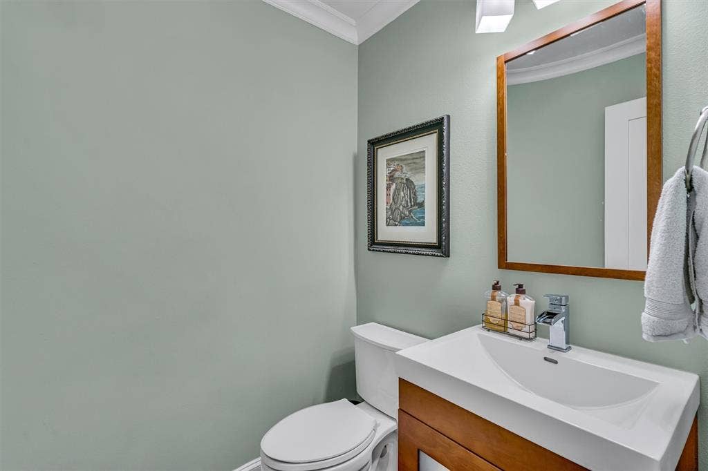 4242 Travis Street, #102, Dallas, TX 75205 Modern vanity with an integrated sink, polished chrome faucet, wood-finish cabinetry, and a framed mirror