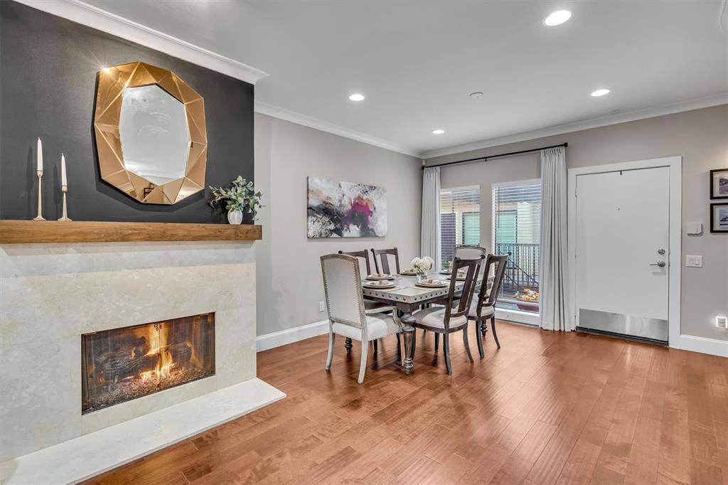 4242 Travis Street, #102, Dallas, TX 75205 Hardwood flooring throughout, stone-clad fireplace with wood mantle, recessed lighting, and crown molding.