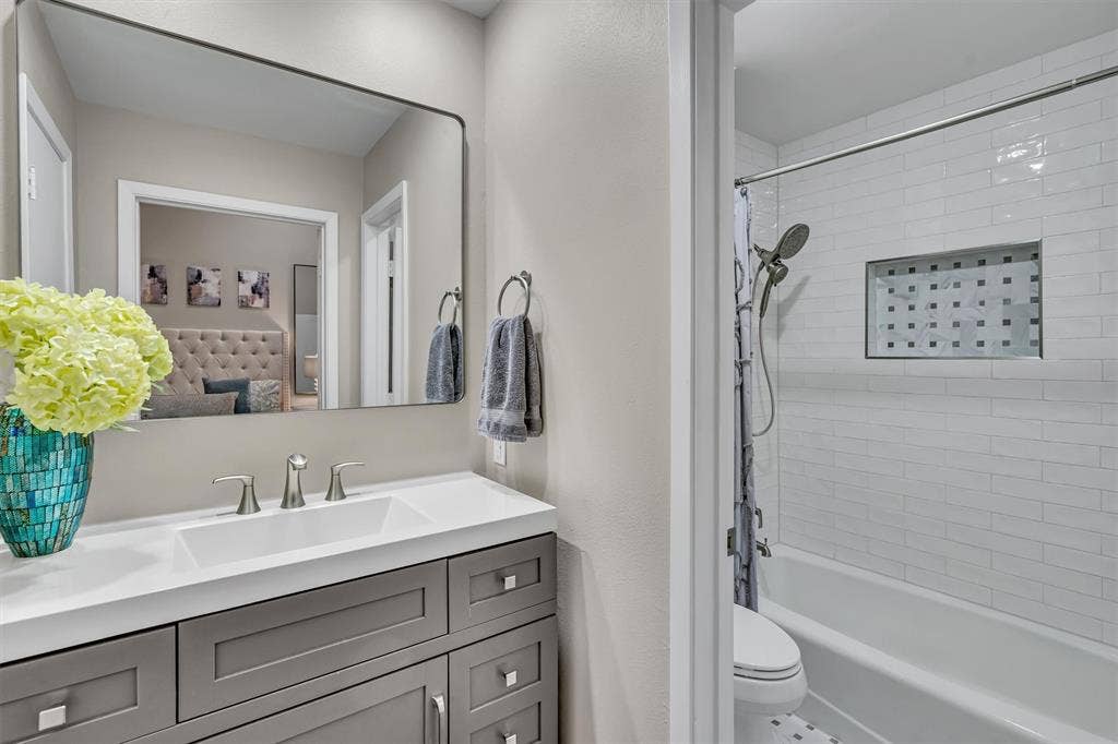 4242 Travis Street, #102, Dallas, TX 75205 Modern primary bathroom featuring a dark wood-finish vanity, white quartz countertop, and polished chrome fixtures