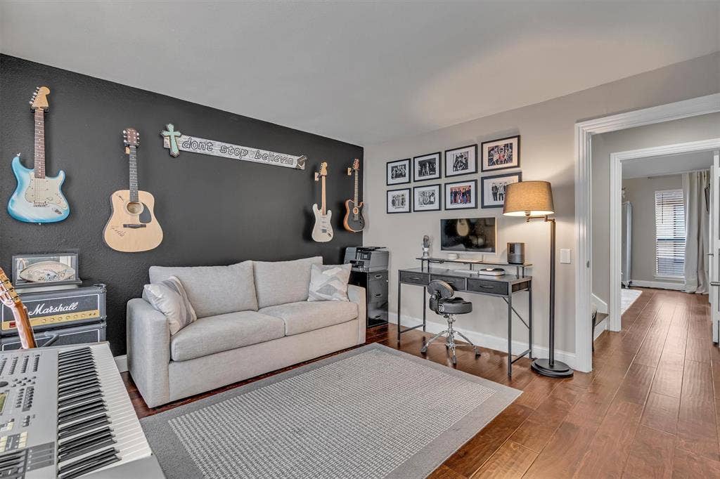 4242 Travis Street, #102, Dallas, TX 75205 Second Bedroom. Dark accent wall, light-toned wall paint, wood-finish flooring, white baseboards, and a doorway with trim