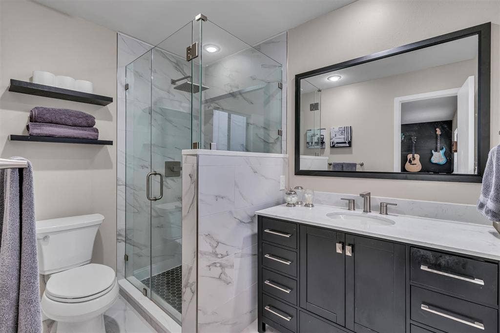4242 Travis Street, #102, Dallas, TX 75205 Walk-in shower with clear glass enclosure and hexagon tile flooring, complemented by a vanity with dark wood cabinetry and a light-toned countertop
