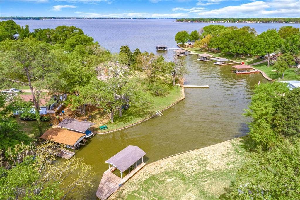 230 Shady Shores Drive, Mabank, TX 75156 Waterfront property featuring a private boat dock with a covered slip, direct access to a spacious lake, and mature trees
