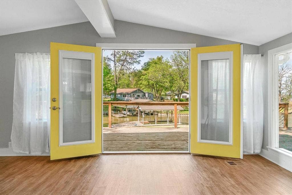 230 Shady Shores Drive, Mabank, TX 75156 Wood-finish flooring, exposed ceiling beams, and bright yellow French doors opening to a wood-plank deck