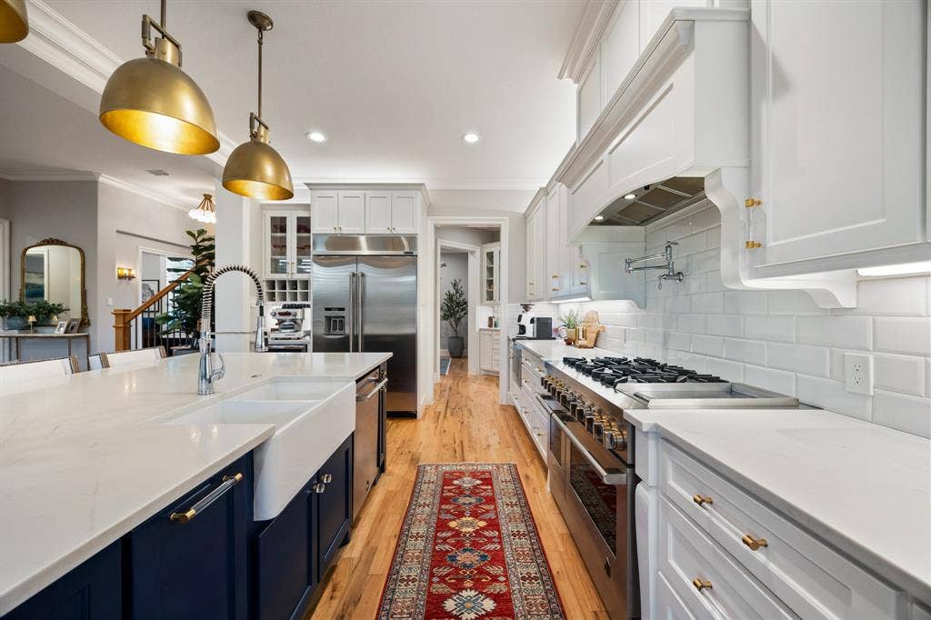 2201 Hanna Court, Midlothian, TX 76065 Deep navy cabinetry and gold pendant lighting add warmth to this open-concept kitchen.