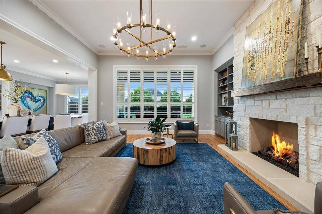2201 Hanna Court, Midlothian, TX 76065 Fireplace framed in floor-to-ceiling stone grounds the living room, wrapped in oversized windows.