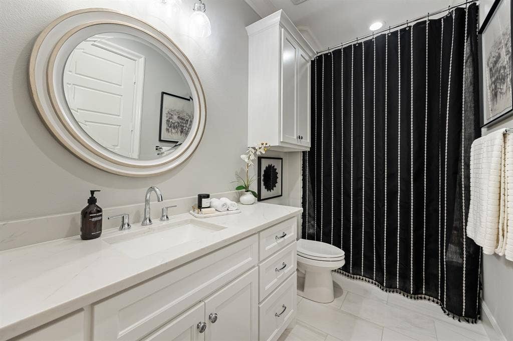 2201 Hanna Court, Midlothian, TX 76065 Clean, bright en-suite bath with a round mirror
