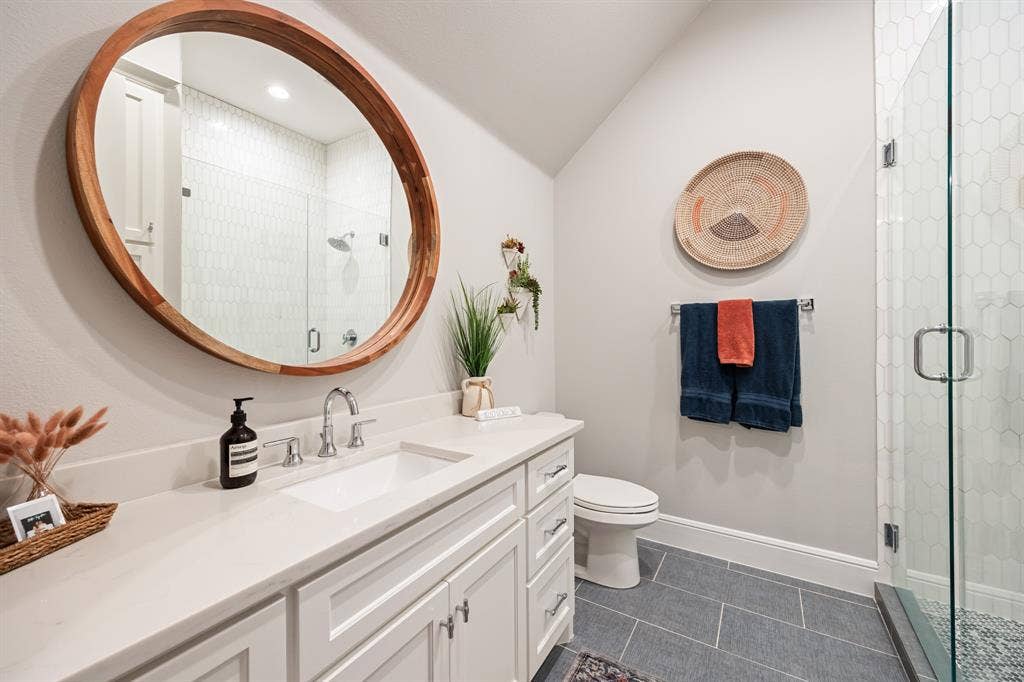 2201 Hanna Court, Midlothian, TX 76065 En-suite bath finished with a warm wood-framed mirror and glass shower.