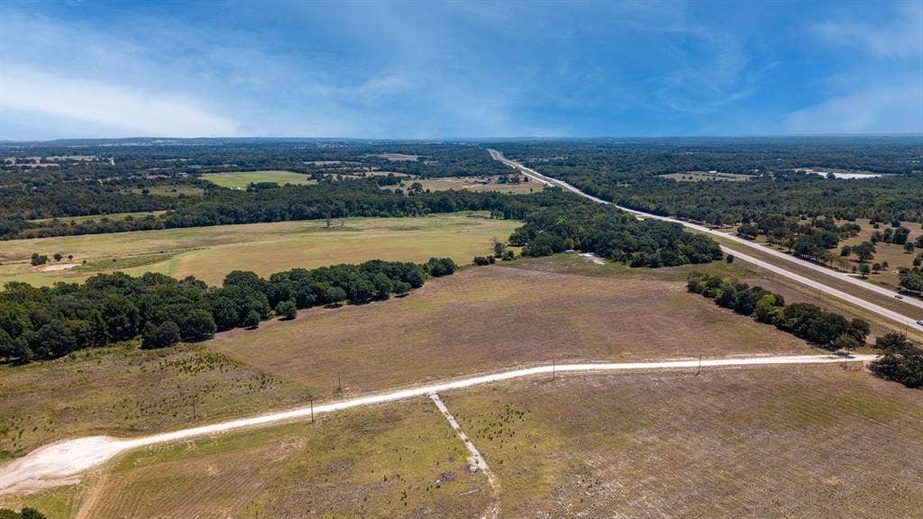 Lot 6 E US HWY 175, Athens, TX 75752 Expansive rural landscape featuring a highway, wooded areas, open fields, and a dirt road