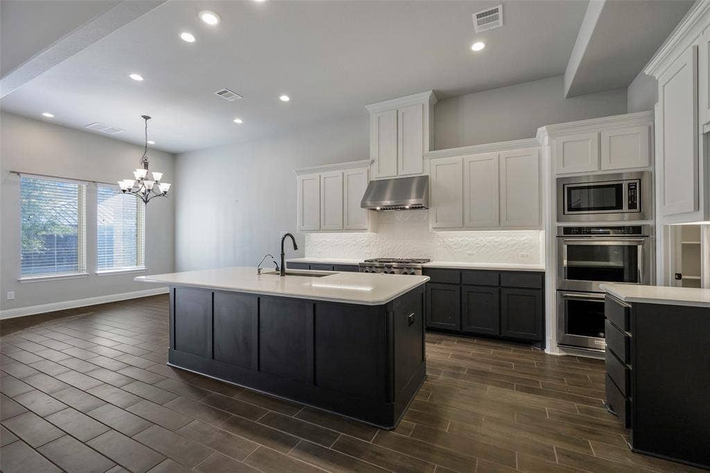 941 Leola Lane, Allen, TX 75013 Open-concept kitchen with a central island, recessed lighting, stainless steel appliances, white subway tile backsplash, and wood-finish flooring