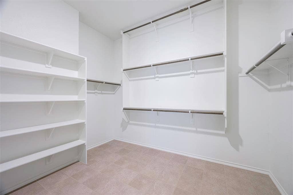 941 Leola Lane, Allen, TX 75013 Expansive closet featuring built-in shelving, multiple hanging rods, and light-toned tile flooring