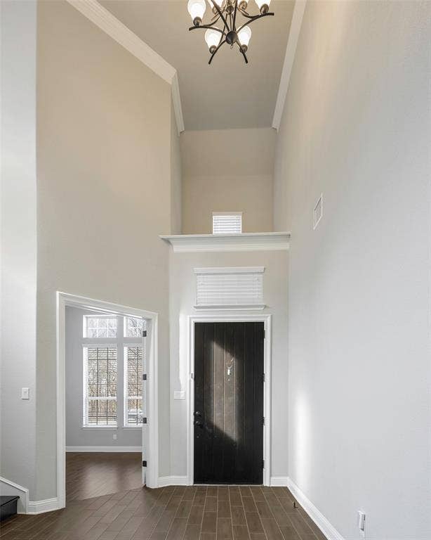 941 Leola Lane, Allen, TX 75013 Soaring ceilings with crown molding, dark wood-finish flooring, a dark paneled entry door, an upper window, and a chandelier