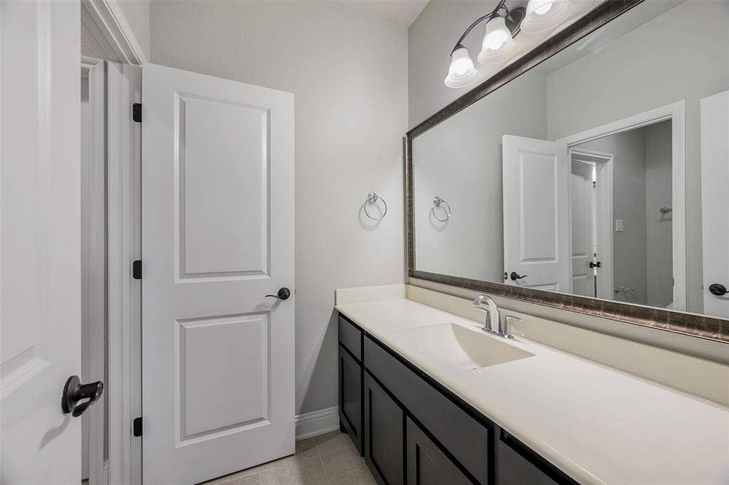 941 Leola Lane, Allen, TX 75013 Extended vanity with an integrated sink, polished chrome faucet, dark cabinetry, and a large framed mirror