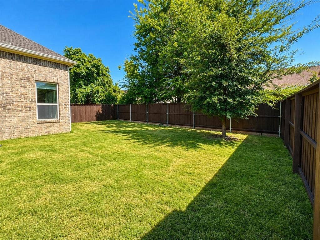 941 Leola Lane, Allen, TX 75013 Expansive backyard featuring a manicured lawn, established tree, and privacy fencing