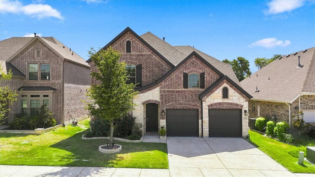 3109 Taunton Way, McKinney, TX 75069 Brick and stone facade with dark shutters, dual garage doors, arched entryway, and established landscaping
