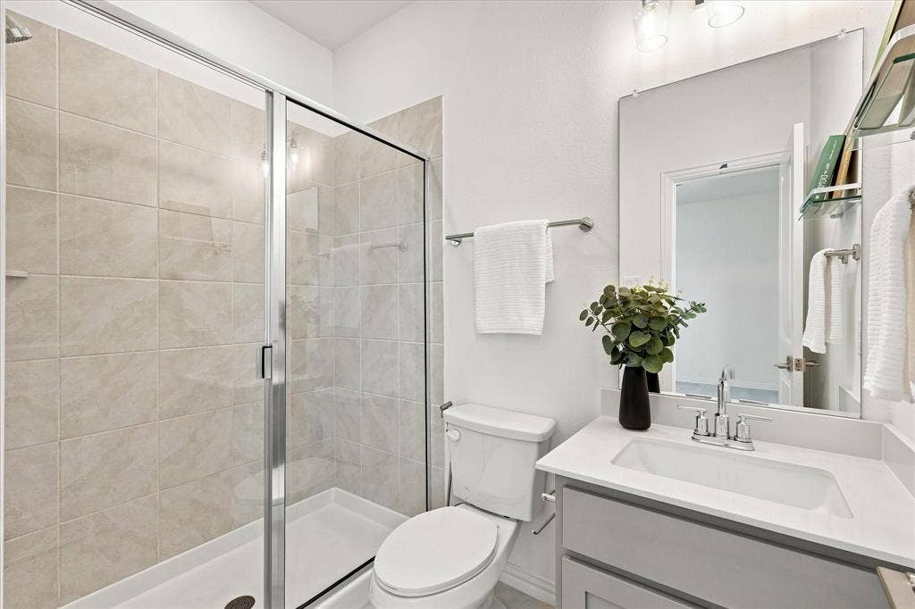 3109 Taunton Way, McKinney, TX 75069 Glass-enclosed shower with tile surround, single vanity with integrated sink, chrome faucet, and expansive wall mirror