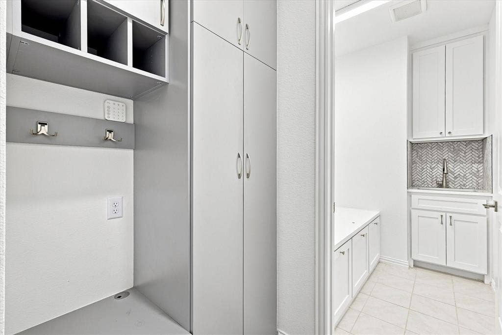 3109 Taunton Way, McKinney, TX 75069 Built-in cabinetry with open shelving, hanging hooks, and a dedicated utility sink with a herringbone tile backsplash