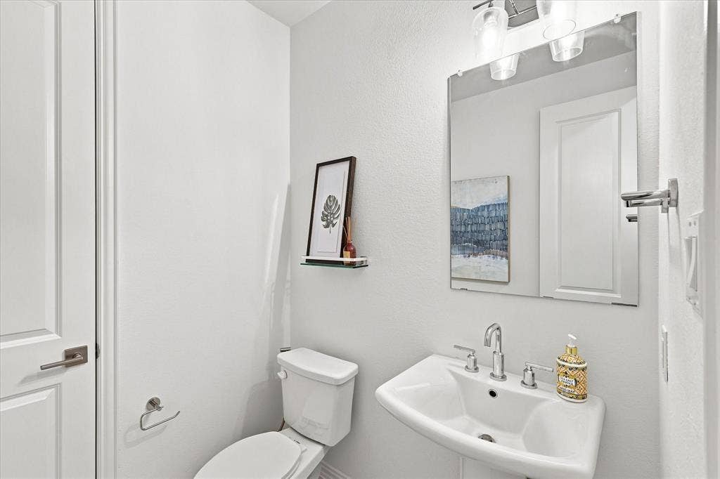 3109 Taunton Way, McKinney, TX 75069 Pedestal sink with chrome fixtures, large wall mirror, and modern overhead lighting