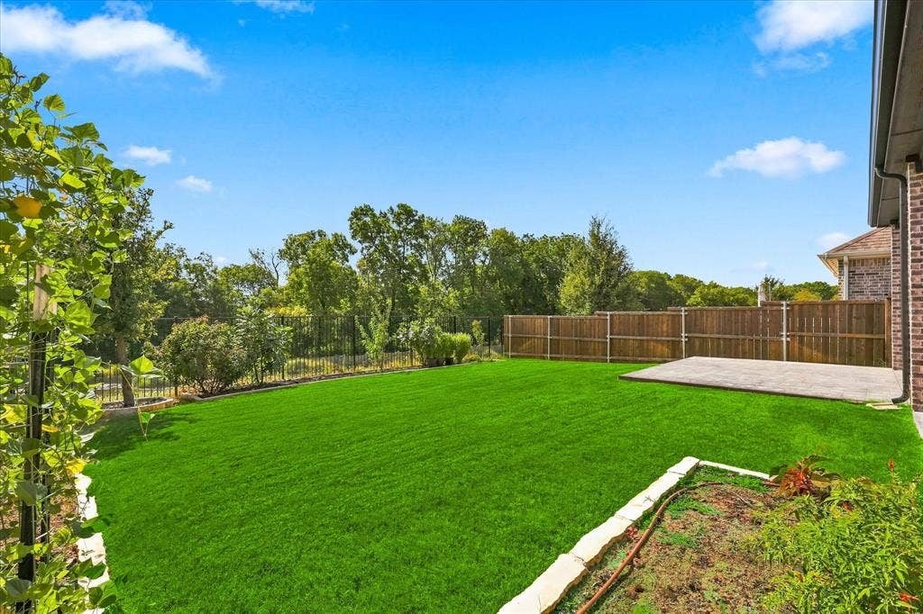 3109 Taunton Way, McKinney, TX 75069 Expansive green lawn, concrete patio, wood privacy fencing, and a brick-sided exterior with gutters