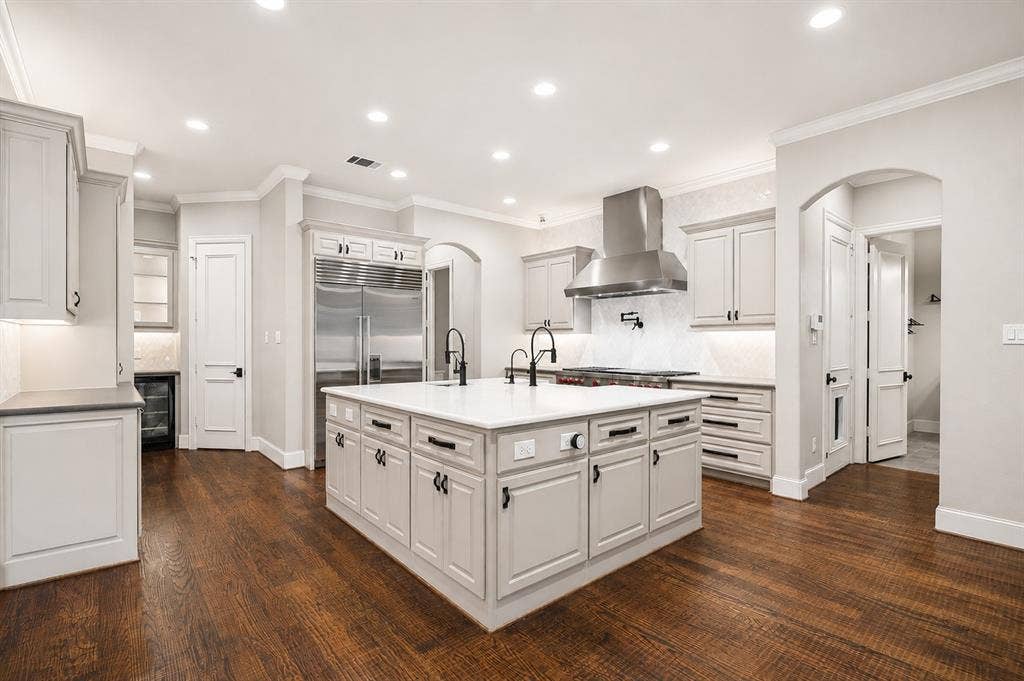 424 Wyndemere Boulevard, Heath, TX 75032 Gourmet kitchen featuring a large central island, white cabinetry, stainless steel appliances, and dark wood-finish flooring