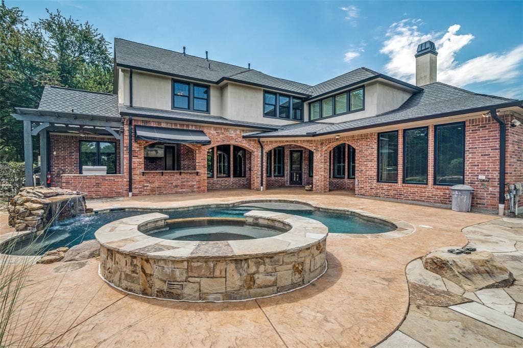 424 Wyndemere Boulevard, Heath, TX 75032 Spacious backyard featuring a custom-shaped swimming pool, integrated spa, stone waterfall, and expansive stamped concrete patio