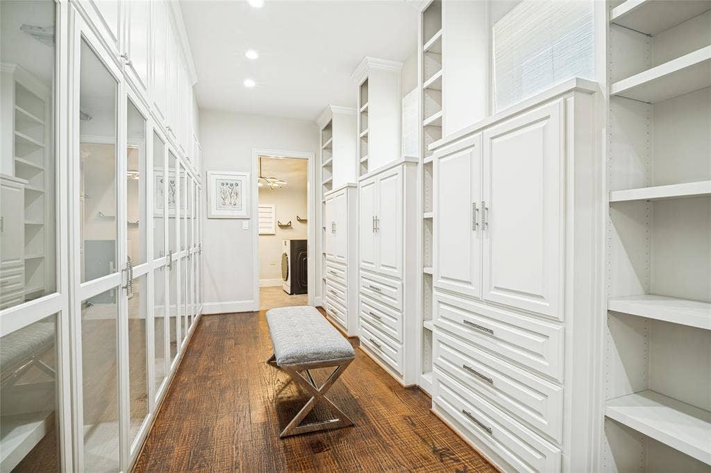 424 Wyndemere Boulevard, Heath, TX 75032 Luxurious walk-in closet featuring floor-to-ceiling white cabinetry with glass-front doors, open shelving, and wood-finish flooring