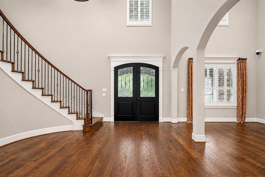 424 Wyndemere Boulevard, Heath, TX 75032 Hardwood flooring, curved staircase with wrought iron balusters, double entry doors, arched doorways, and tall windows with plantation shutters