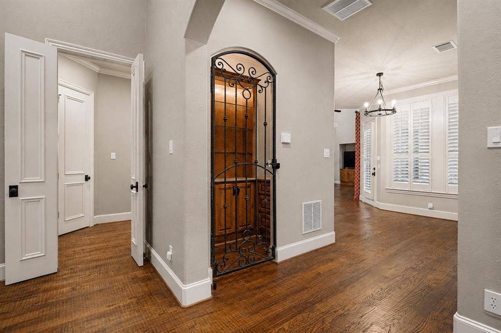 424 Wyndemere Boulevard, Heath, TX 75032 Wood-finish flooring, white trim, arched doorway, wrought iron gate, and ceiling-mounted chandelier